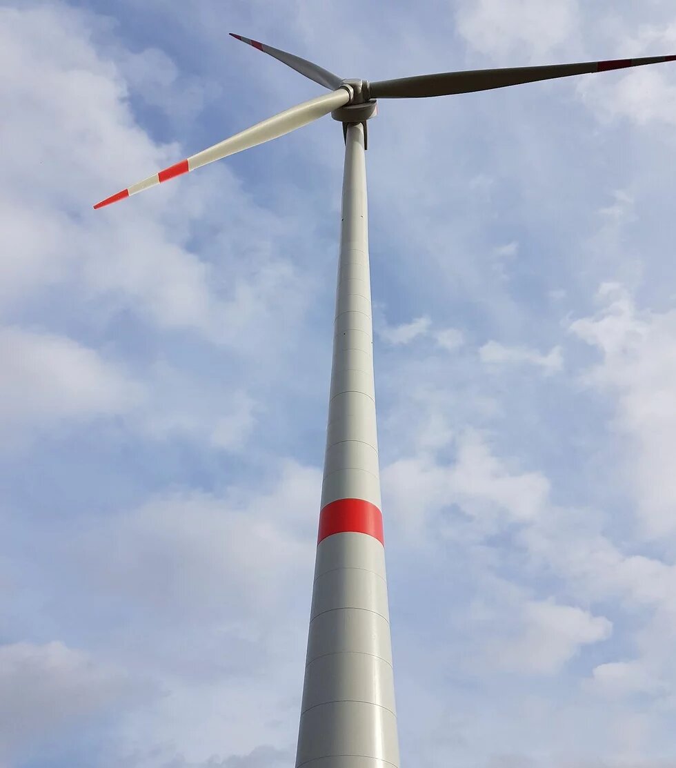 Windrad ragt in einen blauen Himmel mit weißen Wolken